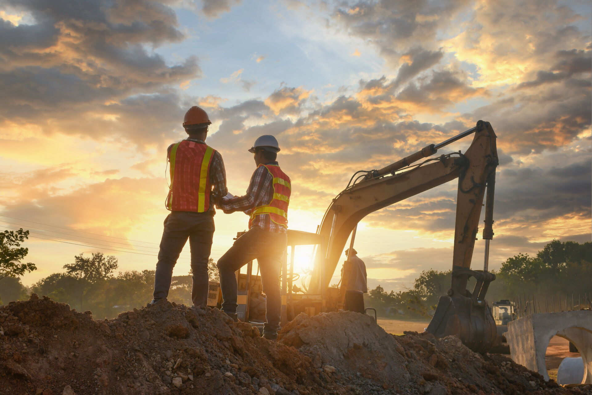 Zwei Bauarbeiter mit Helm und Bagger im Abendlicht. Bauprojekt von Weier Bau.