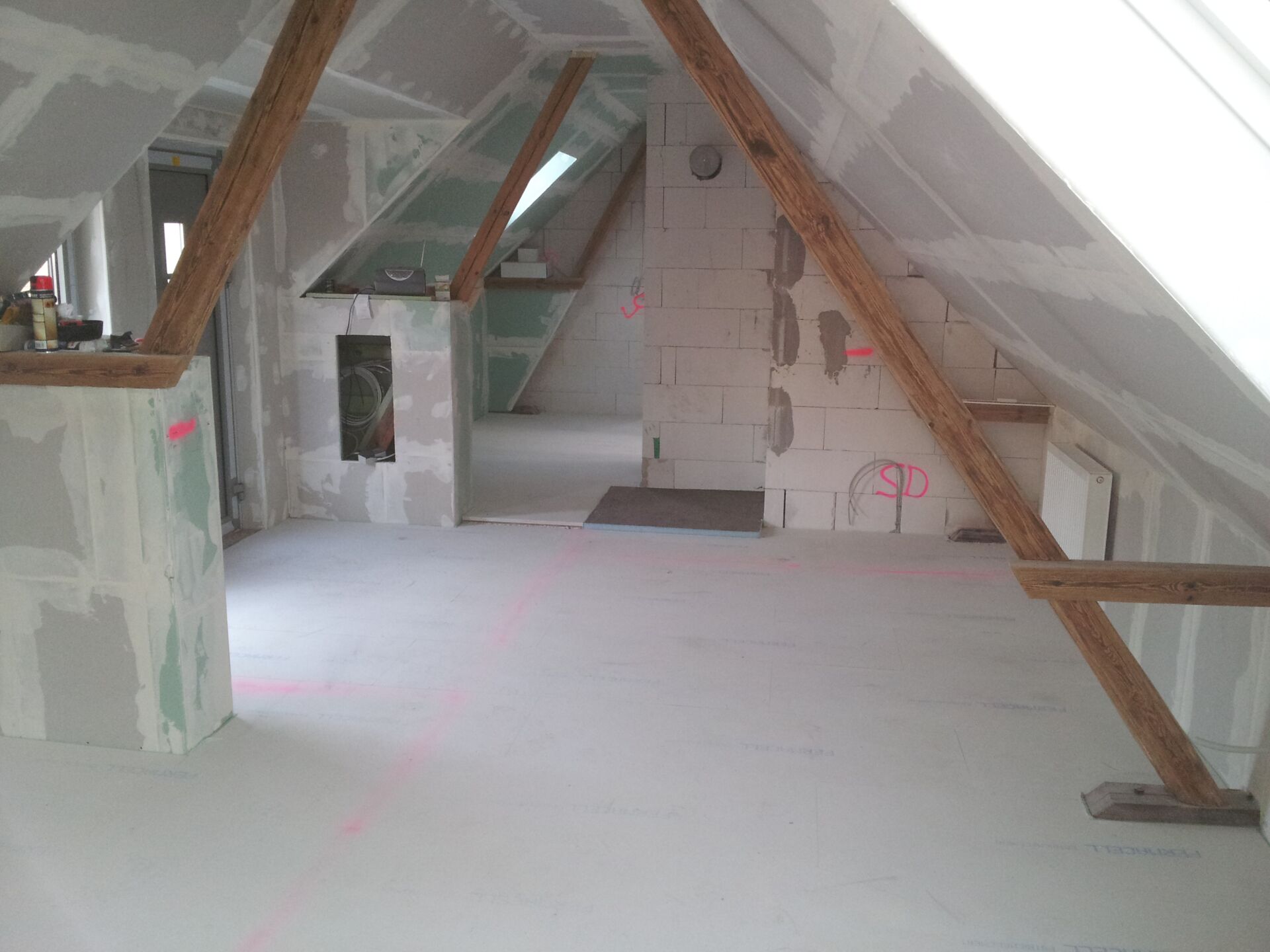Dachgeschoss im Ausbau mit Trockenbauwänden und Holzbalken; professionelle Gestaltung durch Weier Bau.