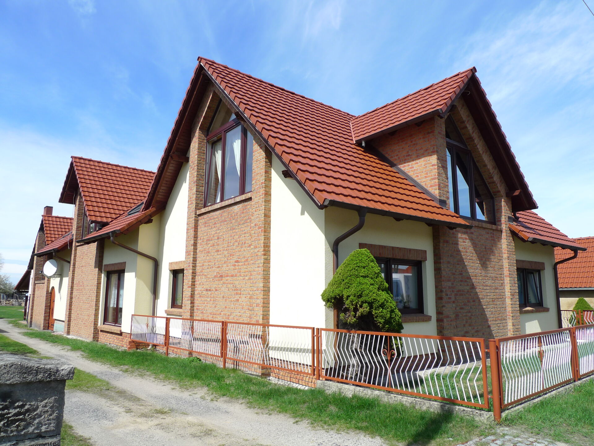 Attraktiver Winkelbungalow mit Klinkerfassade und roten Ziegeln, umgeben von Grün; gebaut von Weier Bau.