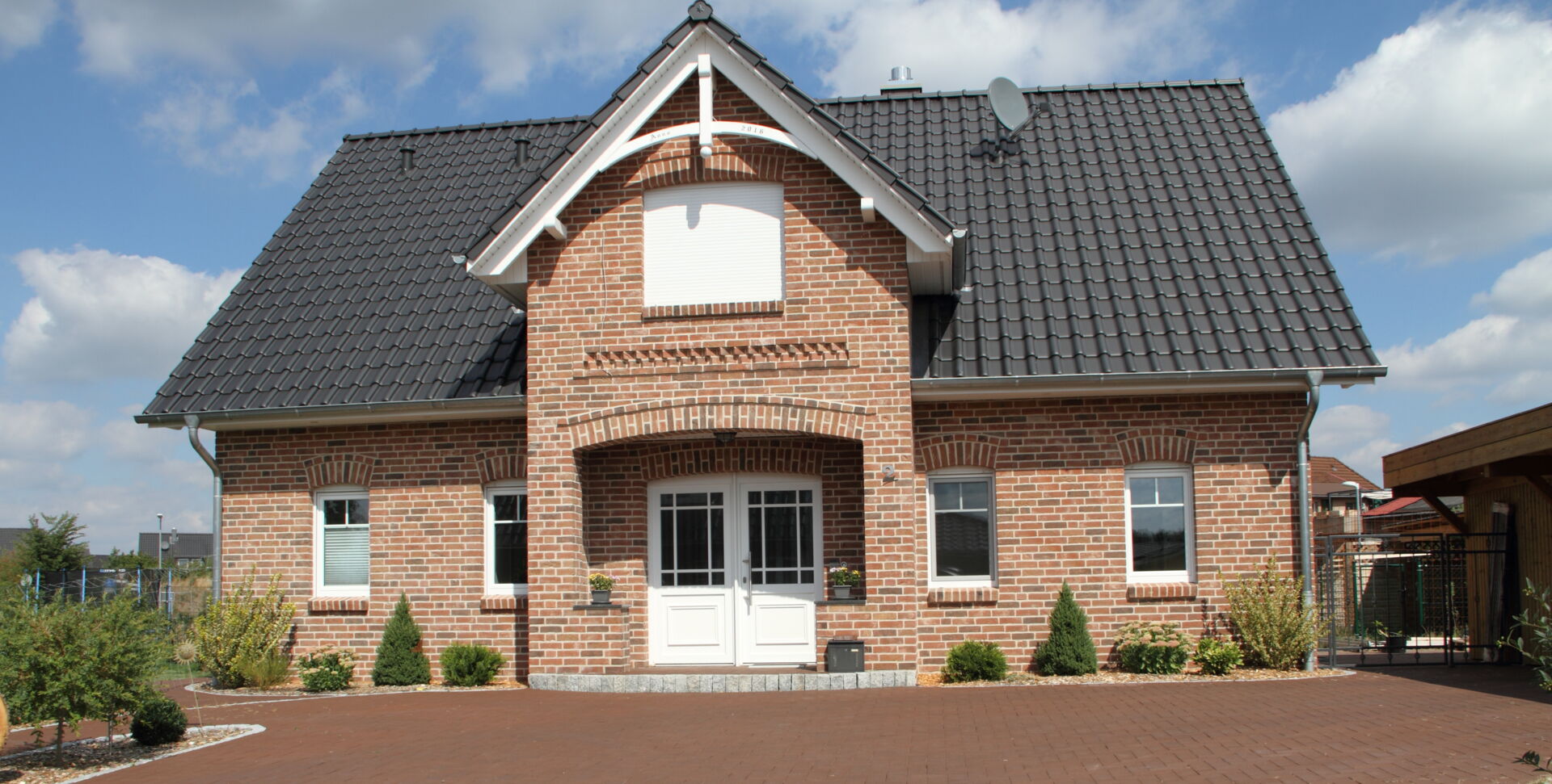 Einfamilienhaus mit Klinkerfassade, Gaube und gepflasterter Auffahrt; gebaut mit der Qualität von Weier Bau.